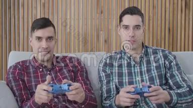 积极的白种人双胞胎<strong>兄弟</strong>玩电子游戏。 穿着蓝色衬衫的男人，他穿着红色衬衫的<strong>兄弟</strong>姐妹，笑着