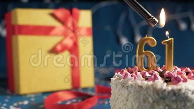 白色生日蛋糕数字61金蜡烛用打火机燃烧，蓝色背景灯和礼品黄色盒子用红色系起来