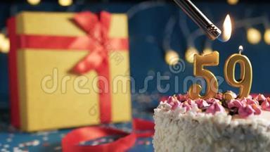 白色生日蛋糕数字59金蜡烛用打火机燃烧，蓝色背景灯和礼品黄色盒子用<strong>红色系</strong>起来