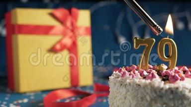 由打火机点燃的79根金色蜡烛的白色生日蛋糕，蓝色背景的灯和黄色礼品盒用<strong>红色系</strong>起来