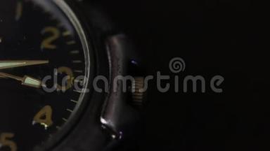桌子上有一只手表。 部分表盘可见.. 第二只手移动。 在黑色背景下拍摄特写镜头