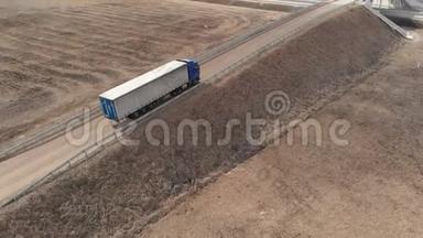 一辆<strong>大型卡车</strong>和一辆拖车沿着土路行驶，在附近寻找掉头的地方