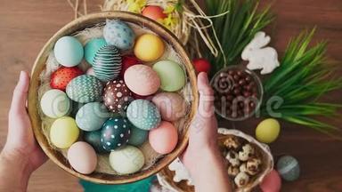 双手提着装满五颜六色的复活节彩蛋的篮子，摆在木桌上。 复活节节日装饰品，复活节