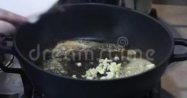 一个女人在热锅里用融化的黄油<strong>放入</strong>切碎的大蒜