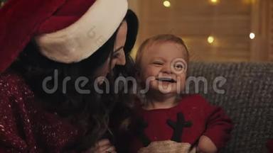 亲近圣诞老人帽里微笑的白种人妈妈和她可爱的可爱的孩子家庭假期和新年的概念