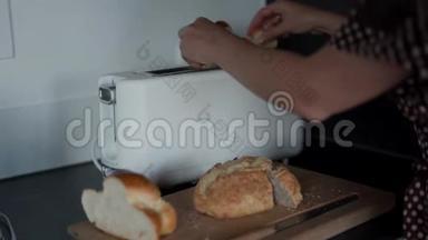 女人在早上准备烤面包机，在家里的厨房里用白色烤面包机。 关门