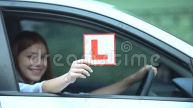 微笑的女孩在车窗上，驾驶课程，左撇子的交通中显示l板