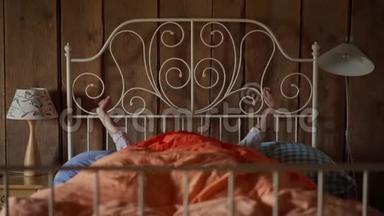 美丽的年轻女子在一张白色的锻铁床上醒来，床上有彩色的床上用品