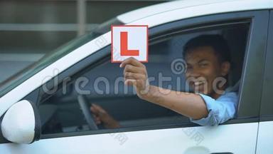 微笑的男孩在车窗上展示l板，驾驶课程，右手交通