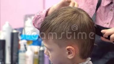 理发师用剪刀在男孩的头上剪头发。 侧视，造型师双手特写..
