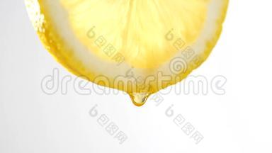 在白色背景下缓慢地从柠檬片中滴下蜂蜜