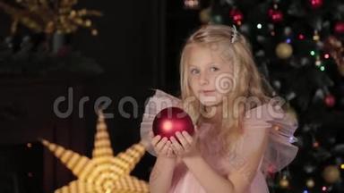 一个十岁的女孩靠近新年树，手里拿着一个新年玩具。 2020年新年。