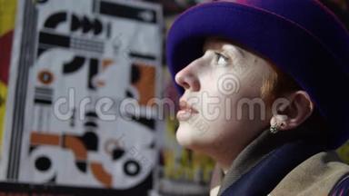 女人的脸戴着<strong>蓝色</strong>的帽子，背景上看着海报，贴着现代的城墙。