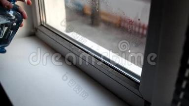 男人在家里洗窗户。 用洗<strong>水喷雾</strong>和除尘器清洗窗户。