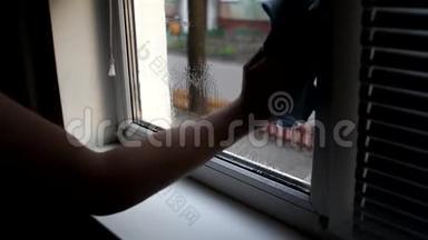 男人在家里洗窗户。 用洗<strong>水喷雾</strong>和除尘器清洗窗户。