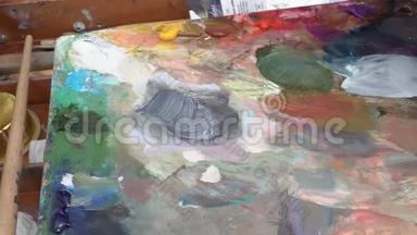 创意画家将油画颜料的调色板混合在画架上。 近距离观看