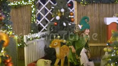 快乐可爱的女孩穿着精灵服装在圣诞节地区玩。 圣诞老人`帮手在玩玩具。 宝贝庆祝，快乐