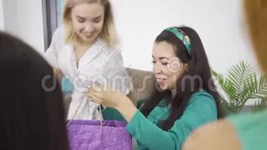 年轻的白种人金发女孩拥抱她怀孕的黑发朋友，并送她的礼物在紫罗兰礼品袋。 四.