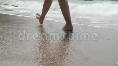 活跃的赤脚妇女走在沿海的沿海地带。 在沙滩上留下脚印