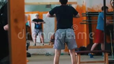 体育训练-在健身房锻炼的男人-一个穿着<strong>蓝色</strong>短裤的男人蹲在<strong>前台</strong>，体重增加