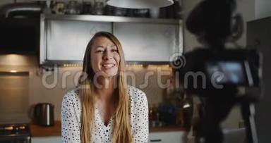 快乐年轻美丽的<strong>美食博主</strong>女人用专业相机在厨房慢动作拍摄新的vlog视频。