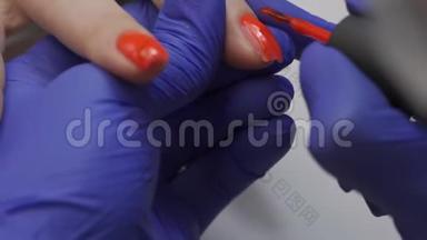 特写专业美容师美甲大师打磨指甲.. 女人正在修指甲。 用红色盖住指甲