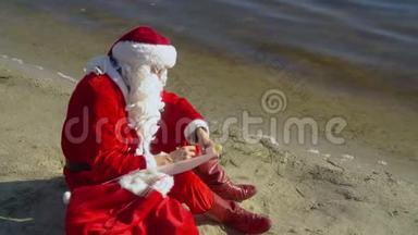 圣诞老人坐在湖边的沙滩上，拿着一个礼品袋，把一些东西写在清单上。 圣诞老人受伤了