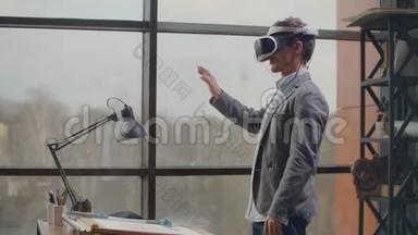 男工程师在一个虚拟现实头盔附近的大窗口用手模仿的工作界面