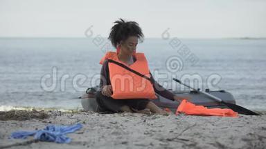 少女在洪水中幸存下来，坐在船边，拿着失去父母的救生衣