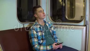 一个年轻人在地铁列车上用耳机听音乐。 旧地铁车