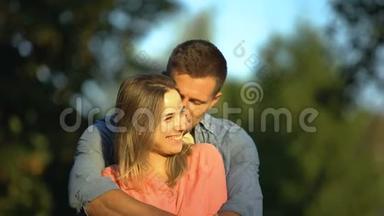 年轻的微笑情侣拥抱阳光公园，糖果花期，<strong>真情</strong>
