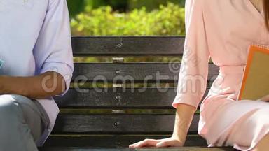学生们拿着放在长凳上的书，男生牵着少女的手