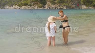 妈妈准备女儿在阳光明媚的日子在海边拍照。 在海边与模特合作的摄影师