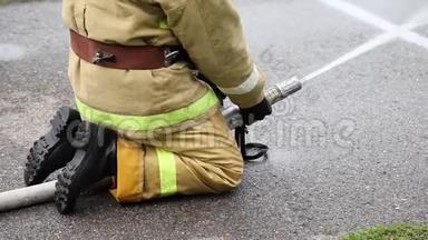 一名消防队员坐着，用消防水带灭火