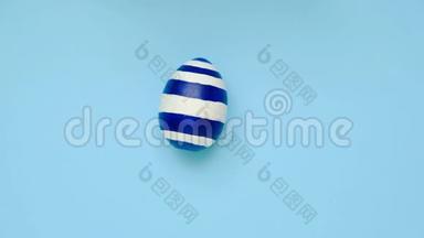 复活节彩蛋在蓝色桌子上旋转。 鸡蛋时髦的彩色经典蓝色，白色和金色。 复活节快乐。 最小