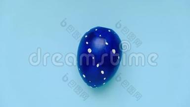 复活节彩蛋在蓝色桌子上旋转。 鸡蛋时髦的彩色经典蓝色，白色和金色。 复活节快乐。 最小