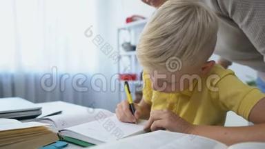 勤奋的男孩子在办公桌前做作业，妈妈表扬儿子，摸着头