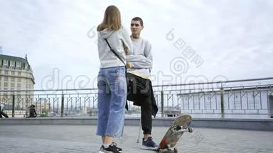 一条腿拄着拐杖，滑板的年轻人在街上和他的女朋友聊天。 残疾人的积极生活