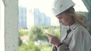 女<strong>建筑工程</strong>师手持智能手机站在施工现场