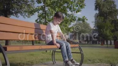 悲伤孤独的小男孩坐在公园的长凳上。 <strong>可爱</strong>的孩子独自<strong>呆</strong>在户外。 夏日休闲