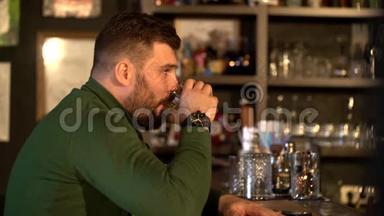 一个留胡子的男人坐在酒吧喝威士忌，和一个女朋友<strong>通电</strong>话