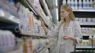 广告，商业，食品，健康概念-在超市里站在冰箱前的女人选择购买