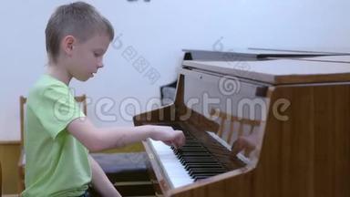 小男孩在学校音乐课上练习弹钢琴。