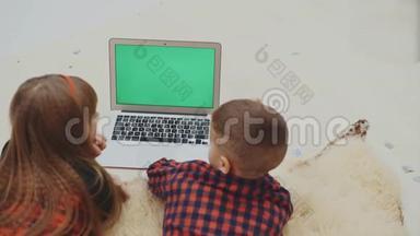 孩子们，看着笔记本电脑<strong>屏</strong>幕与跟踪色度键<strong>绿</strong>色<strong>屏</strong>幕，躺在白色地毯上的假期晚上。