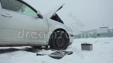 人们在冬天降雪时修理或修理破车。 汽车故障或问题。 汽车电池和一套工具