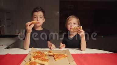 两个男孩深夜在家厨房吃披萨。 一个人在家。