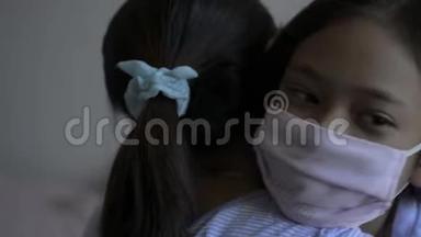 母亲和女儿<strong>拥抱</strong>在一起，戴着防护面具，在COVIC19疫情期间。