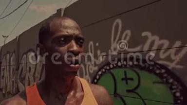 精疲力竭的黑人非洲美国职业跑步运动员在城市跑步后步行降温，擦去汗水