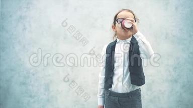 小女商人喜欢喝茶。 在此期间，它是在灰色背景上。 穿着商务服。