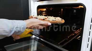 一个女人把<strong>披萨</strong>放进烤箱。 在电对流炉里煮<strong>意大利披萨</strong>。 带有莫扎拉奶酪的<strong>披萨</strong>